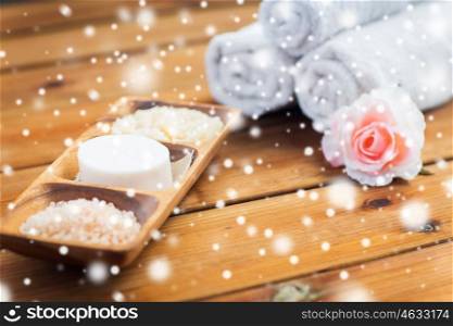 beauty, spa, bodycare, natural cosmetics and bath concept - soap with himalayan salt and scrub in wooden bowl on table over snow