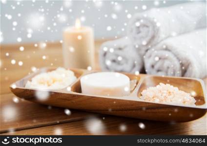beauty, spa, bodycare, natural cosmetics and bath concept - soap with himalayan salt and body scrub in wooden bowl on table over snow