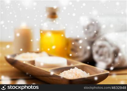 beauty, spa, bodycare, natural cosmetics and bath concept -soap with himalayan salt and scrub in wooden bowl on table over snow