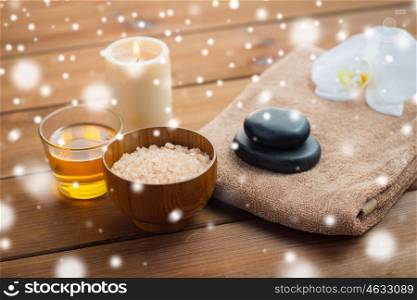 beauty, spa, bodycare, natural cosmetics and concept - himalayan pink salt with honey in glass and bath towel on wooden table over snow