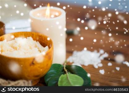 beauty, spa, bodycare, natural cosmetics and wellness concept - body scrub and candle on wood over snow