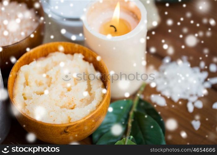 beauty, spa, bodycare, natural cosmetics and wellness concept -body scrub and candle on wood over snow