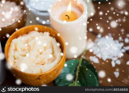 beauty, spa, bodycare, natural cosmetics and wellness concept -body scrub and candle on wood over snow