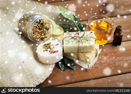 beauty, spa, bodycare, natural cosmetics and wellness concept - close up of handmade soap bars on wooden table over snow