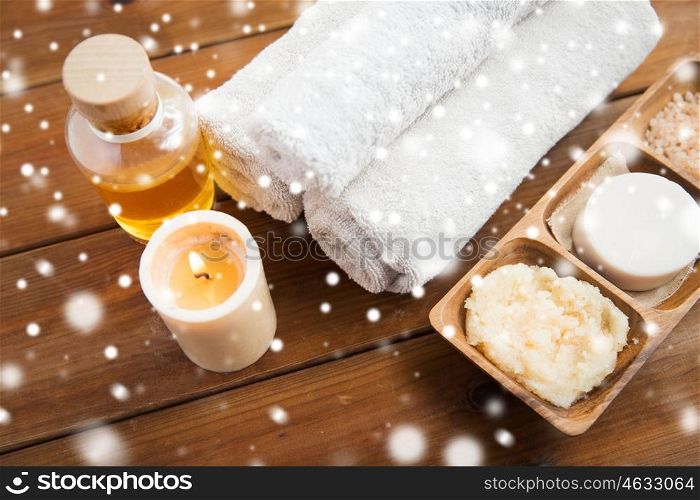 beauty, spa, bodycare, natural cosmetics and wellness concept - close up of soap with candle and bath towels on wooden table over snow