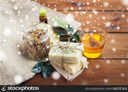 beauty, spa, bodycare, natural cosmetics and wellness concept - handmade soap with honey and herbal tea on wood over snow