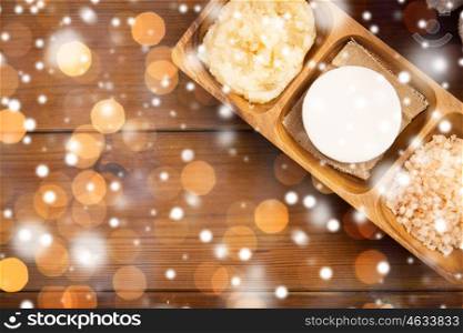 beauty, spa, bodycare, natural cosmetics and wellness concept - soap with himalayan pink salt and scrub in wooden bowl on table over snow