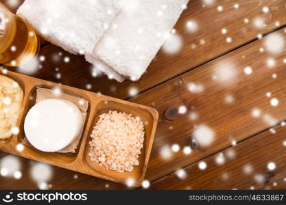 beauty, spa, bodycare, natural cosmetics and wellness concept - soap with himalayan pink salt and bath towels on wooden table over snow