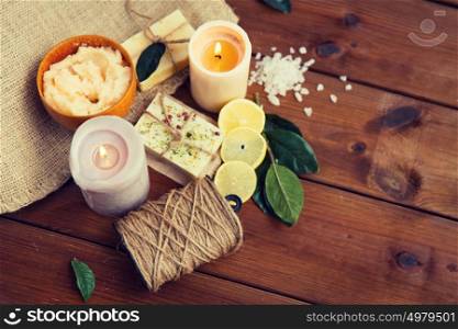 beauty, spa, therapy, natural cosmetics and wellness concept - close up of body care cosmetic products on wood. close up of natural soap and candles on wood