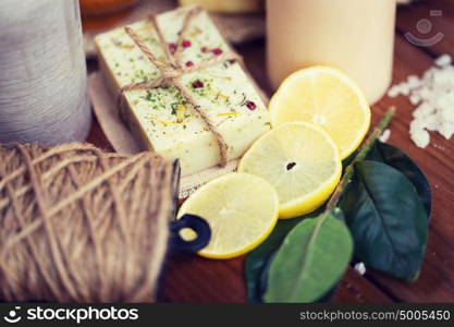 beauty, spa, therapy, natural cosmetics and wellness concept - close up of body care cosmetic products on wood. close up of natural soap and candles on wood