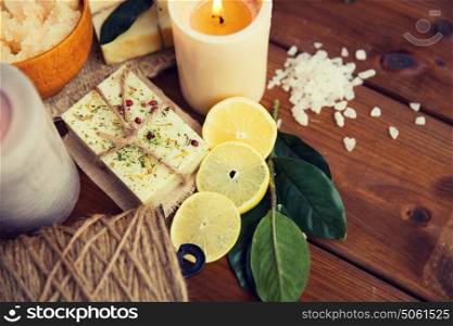 beauty, spa, therapy, natural cosmetics and wellness concept - close up of body care cosmetic products on wood. close up of natural soap and candles on wood