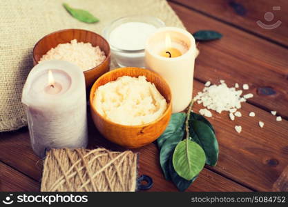 beauty, spa, therapy, natural cosmetics and wellness concept - close up of body scrub with himalayan pink salt and candles on wood. close up of natural body scrub and candles on wood. close up of natural body scrub and candles on wood