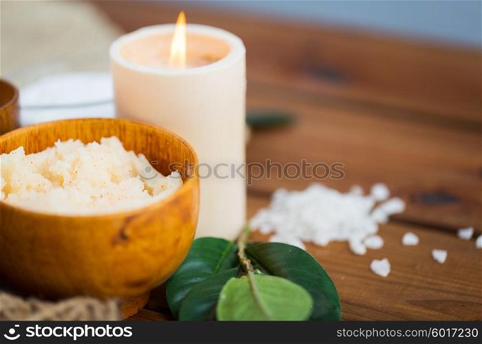 beauty, spa, therapy, natural cosmetics and wellness concept - close up of body scrub and candle on wood
