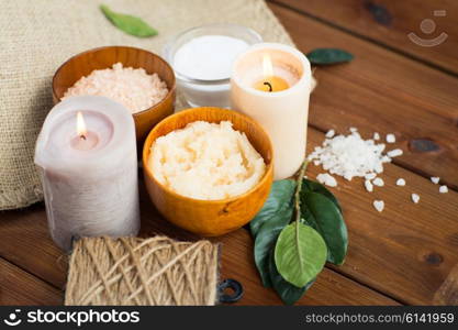 beauty, spa, therapy, natural cosmetics and wellness concept - close up of body scrub with himalayan pink salt and candles on wood