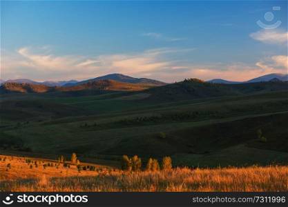Beauty summer evening in the mountains in Altay. Green and yellow meadows, blue sky, purity air.. Beauty summer evening in the mountains