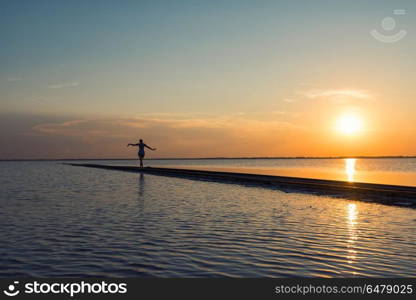 Beauty sunset on salty lake. Woman at railway in the salty lake