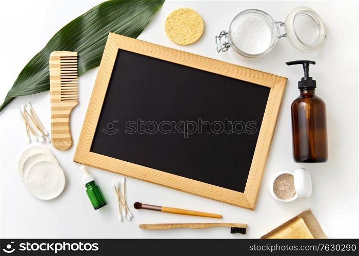 beauty, sustainability and eco living concept - natural cosmetics, bodycare eco products and chalkboard on white background. natural cosmetics and chalkboard