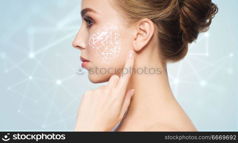 beauty, technology and people concept - beautiful young woman pointing finger to her skin over blue background with low poly shape projection on cheek. beautiful woman with low poly projection on cheek. beautiful woman with low poly projection on cheek