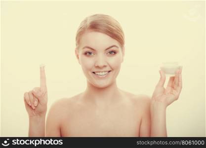 Beauty treatment. Woman applying moisturizing cream on face, holding jar with skin care product, studio shot filtered photo