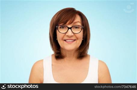 beauty, vision and old people concept - portrait of smiling senior woman in glasses over blue background. portrait of senior woman in glasses over white