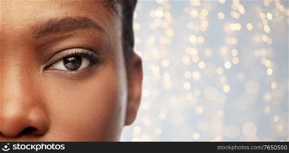 beauty, vision and people concept - close up of face of beautiful young african american woman over festive lights background. close up of face of young african american woman