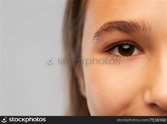beauty, vision and people concept - close up of teenage girl face with brown eyes over grey background. close up of teenage girl face with brown eyes