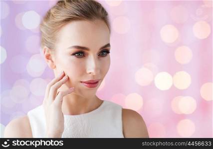 beauty, wedding and people concept - beautiful smiling woman in white dress touching her face over rose quartz and serenity lights background