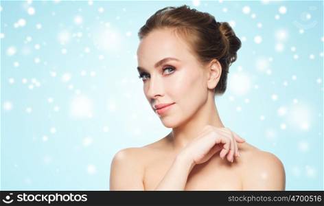 beauty, winter, people and health concept - beautiful young woman face over blue background and snow