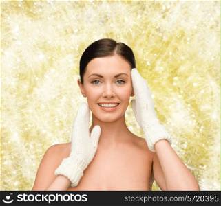 beauty, winter, people and health concept - smiling young woman in white mittens over yellow lights background