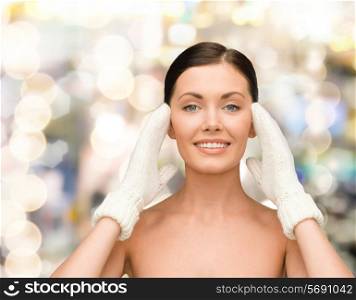 beauty, winter, people and health concept - smiling young woman in white mittens over lights background