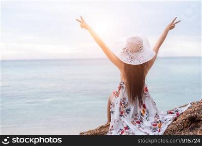 Beauty woman doing cheerful gesture beside the beach. Woman raise two hands and breathing fresh air happily. People and Lifestyles concept. Travel and vacation theme. Back view