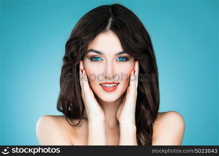 Beauty woman portrait. Beautiful woman with long brown hair. Closeup beauty portrait of a fashion model posing at studio on blue background