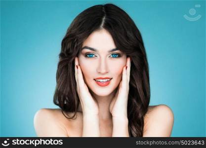 Beauty woman portrait. Beautiful woman with long brown hair. Closeup beauty portrait of a fashion model posing at studio on blue background