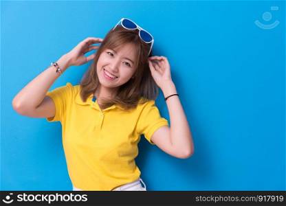 Beauty woman posing with sunglasses in front of blue wall background. Summer and vintage concept. Happiness lifestyle and people portrait theme. Cute and pastel tone.