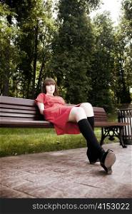 Beauty Woman Sitting On A Park Bench Under The Sunlight