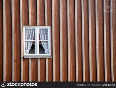 beauty wooden window with curtains in a house facade wall.