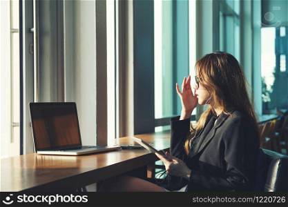 beauty working women black suit clothe brown long hair sunglasses use tablet and computer laptop sitting on chair at her office