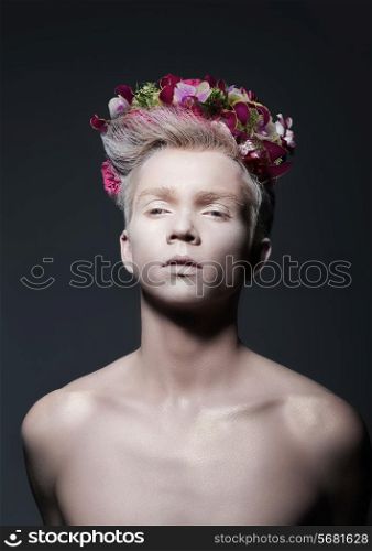 Beauty. Young Man with Wreath of Flowers over Gray