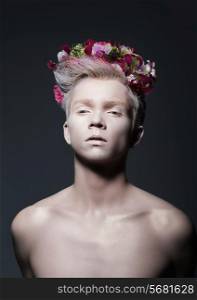 Beauty. Young Man with Wreath of Flowers over Gray