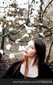 Beauty young woman enjoying nature in spring magnolia flowers. 