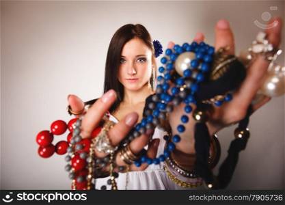 Beauty young woman in summer style with plenty of jewellery, beads in hands gray background