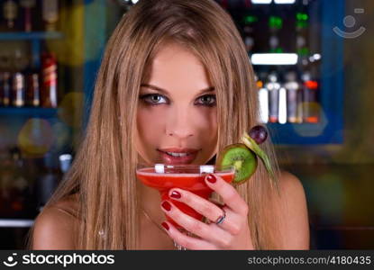 Beauty young woman portrait with a glass drinking a cocktail at a bar