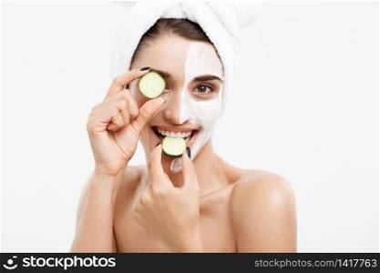 Beauty Youth Skin Care Concept - Portrait Beautiful Caucasian Woman apply cream and holding fresh cucumber in front of her face.Isolated over white background. Beauty Youth Skin Care Concept - Portrait Beautiful Caucasian Woman apply cream and holding fresh cucumber in front of her face.Isolated over white background.