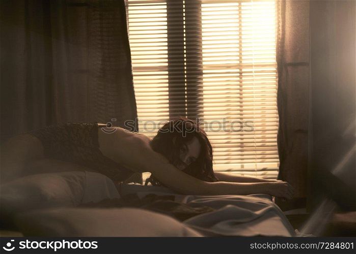 Beautyful nude woman in home interior. Sexy lady with perfect body in bedroom. Sexual portrait of young model pose infront of windows. Erotic figure of naked beauty in room. 