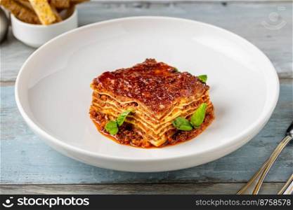 Bechamel sauce and minced meat lasagna on wooden table
