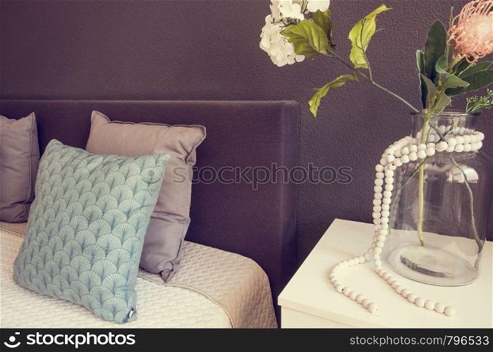 Bed made-up with clean pillows and bed sheets in beauty room. with glass vase and decorative flowers close-up. Bed made-up with clean pillows and bed sheets in beauty room. with glass vase and decorative flowers