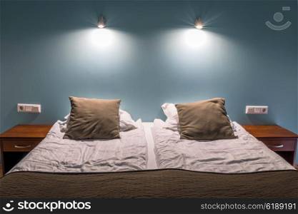 Bed with two brown pillows and lit lamps
