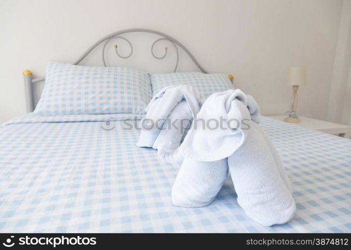 Bedroom. A blue towels and bedding. A lamp at the bedside.