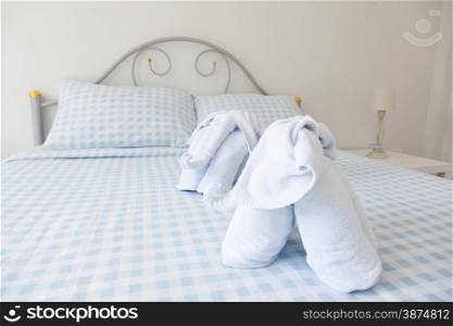 Bedroom. A blue towels and bedding. A lamp at the bedside.