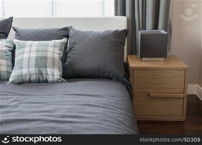 bedroom interior design with checked green pillows on grey bed and decorative table lamp.